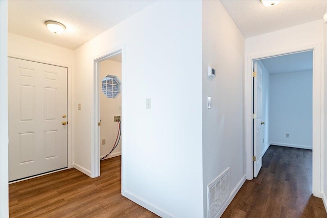 hall featuring dark wood-type flooring and a textured ceiling