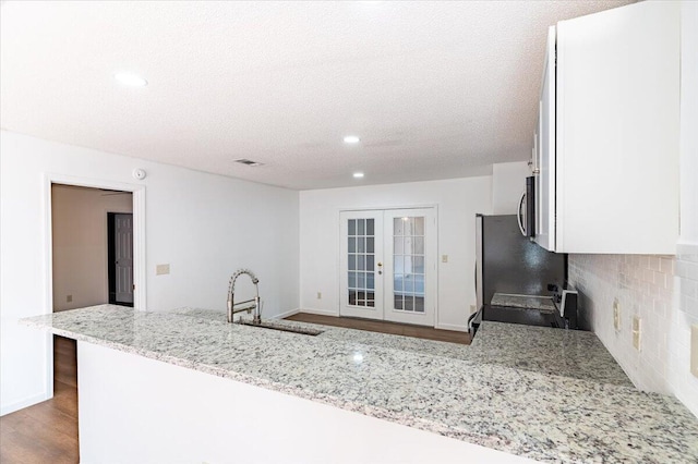 kitchen featuring sink, french doors, range with electric cooktop, hardwood / wood-style flooring, and light stone countertops