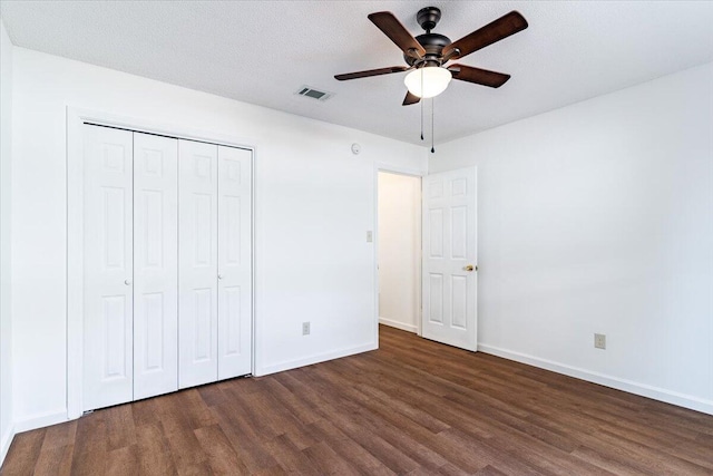 unfurnished bedroom with ceiling fan, a textured ceiling, a closet, and dark wood-type flooring