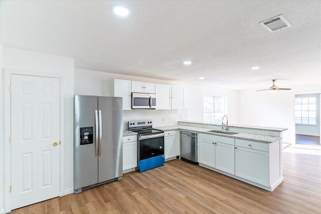 kitchen with appliances with stainless steel finishes, plenty of natural light, sink, and white cabinets