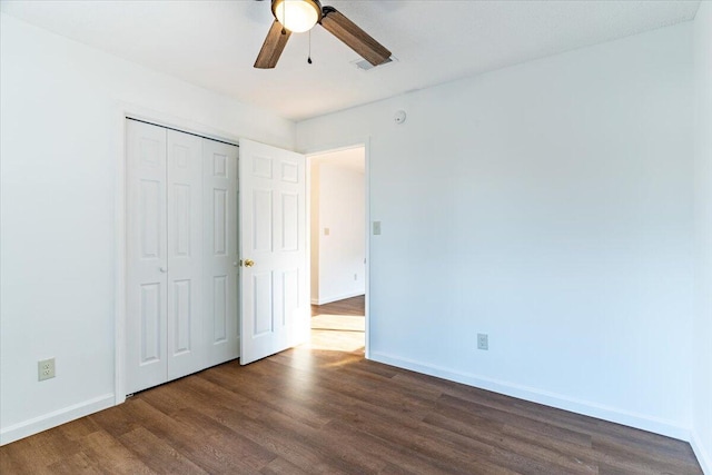 unfurnished bedroom featuring dark wood-type flooring, a closet, and ceiling fan