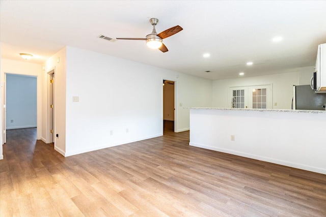 unfurnished living room with french doors, light hardwood / wood-style floors, and ceiling fan