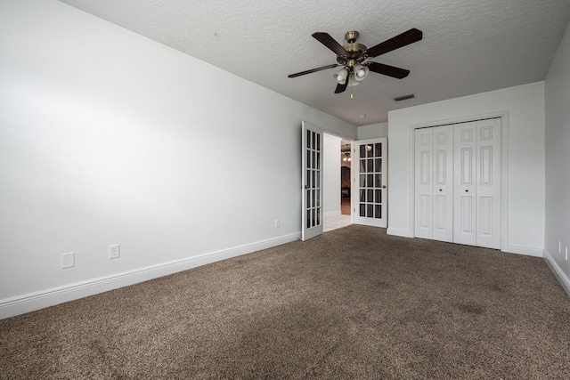 unfurnished bedroom with a closet, ceiling fan, carpet floors, and a textured ceiling