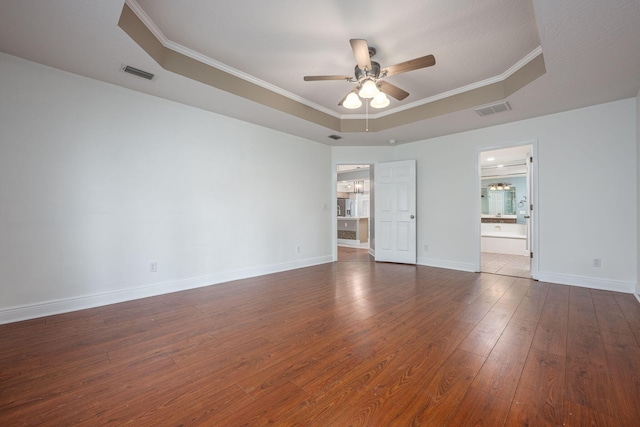 unfurnished room featuring a tray ceiling, ceiling fan, dark wood-type flooring, and crown molding