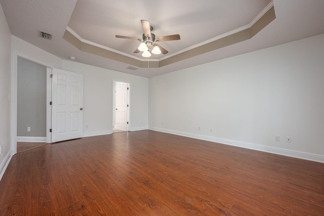 spare room featuring ceiling fan, a tray ceiling, crown molding, and dark wood-type flooring