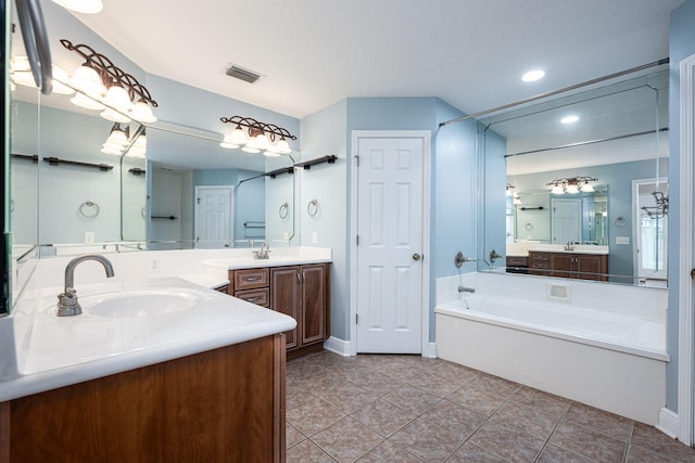 bathroom with vanity, a textured ceiling, tile patterned flooring, and a bath