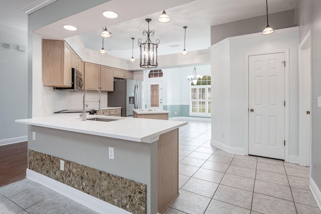 kitchen with light brown cabinets, appliances with stainless steel finishes, pendant lighting, and crown molding