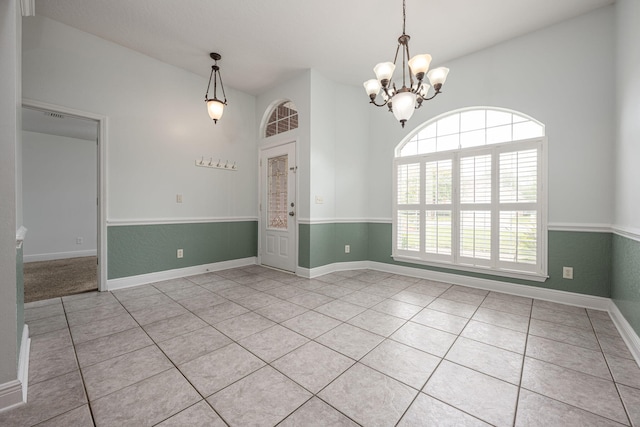 empty room featuring a notable chandelier and light tile patterned floors