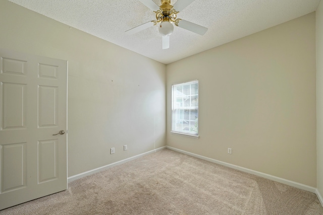 empty room with ceiling fan, light colored carpet, and a textured ceiling