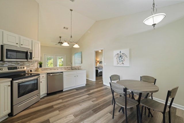 kitchen with decorative light fixtures, stainless steel appliances, and white cabinets