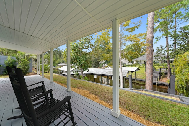 wooden terrace featuring a dock, a yard, and a water view