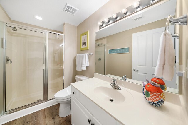 bathroom with walk in shower, wood-type flooring, vanity, and toilet