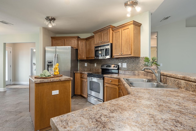 kitchen featuring sink, stainless steel appliances, kitchen peninsula, decorative backsplash, and a kitchen island