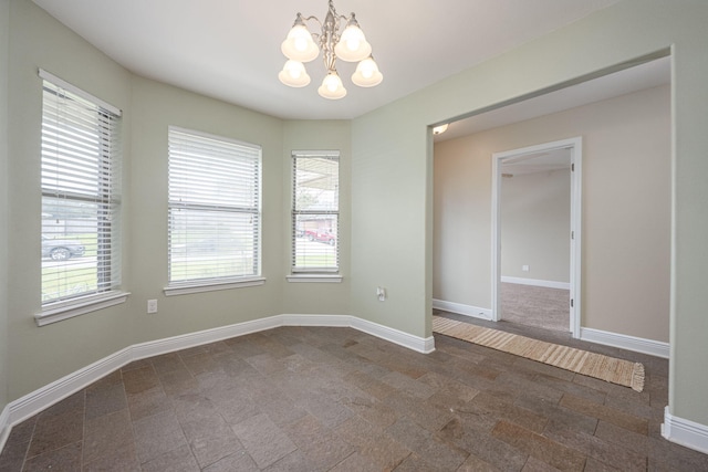 spare room featuring a notable chandelier and a healthy amount of sunlight