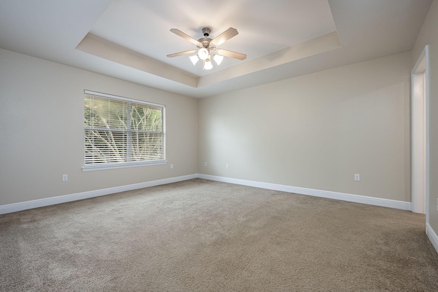 carpeted spare room featuring ceiling fan and a raised ceiling