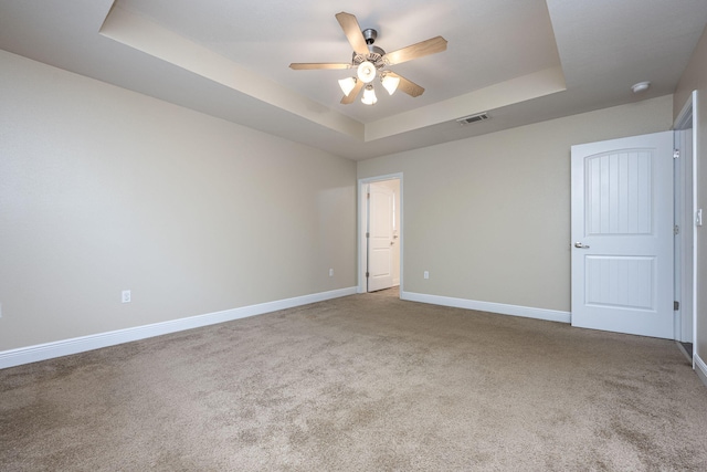 carpeted empty room featuring ceiling fan and a tray ceiling