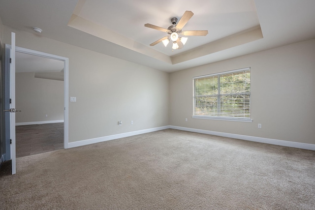 carpeted empty room with ceiling fan and a tray ceiling