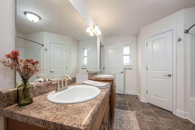 2826 Shoni Dr, Navarre, FL 32566 - bathroom featuring double vanity, baseboards, stone finish flooring, and a sink