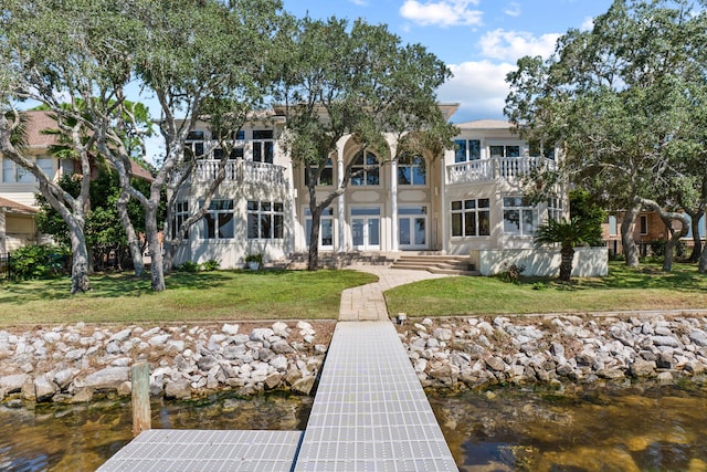 back of property featuring a yard, a water view, and a balcony