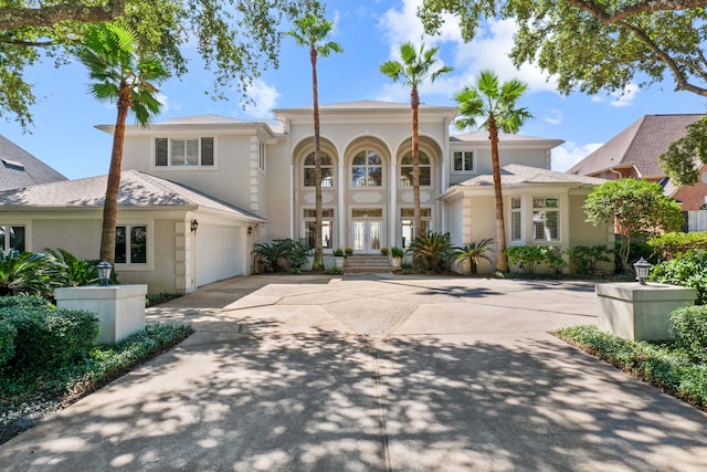 view of front of home with a garage, french doors, driveway, and stucco siding