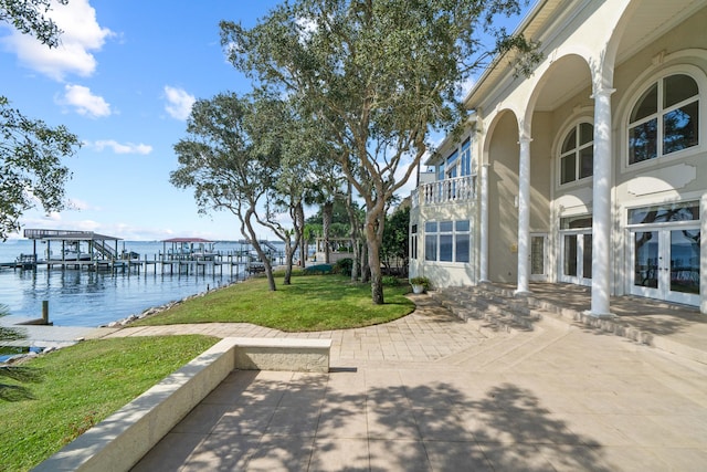 exterior space with a water view, a balcony, a boat dock, and french doors