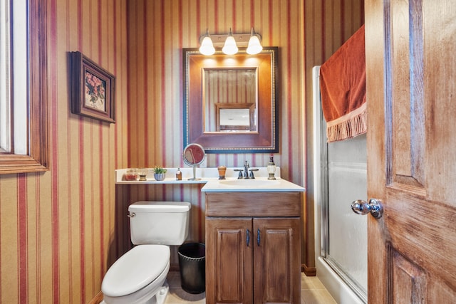 full bath with vanity, a shower with door, toilet, and wallpapered walls