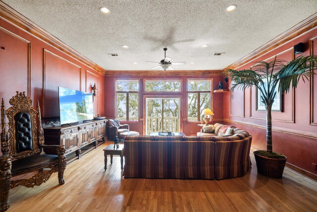 living area featuring crown molding, light wood-style floors, visible vents, and a decorative wall