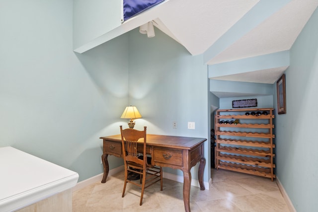 home office featuring light tile patterned floors, baseboards, and vaulted ceiling