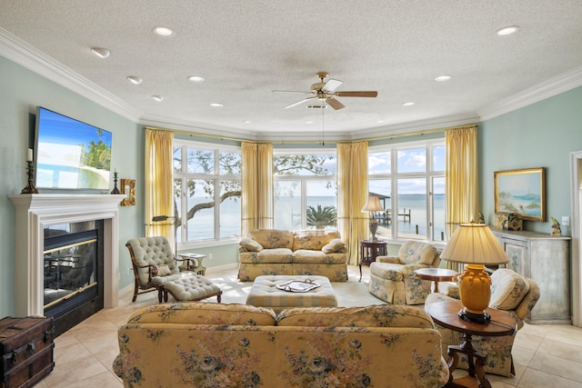 living area featuring light tile patterned floors, a textured ceiling, crown molding, and a glass covered fireplace