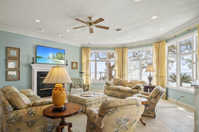 living area with a wealth of natural light, visible vents, crown molding, and a glass covered fireplace