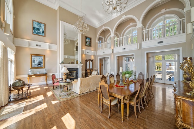 dining room featuring a notable chandelier, wood finished floors, visible vents, a glass covered fireplace, and crown molding