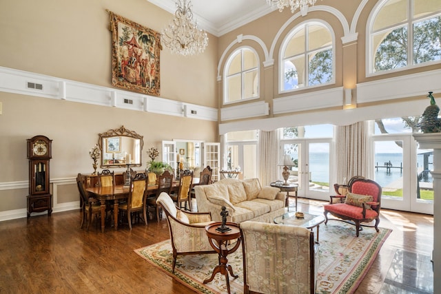 living room with a chandelier, wood finished floors, crown molding, and french doors