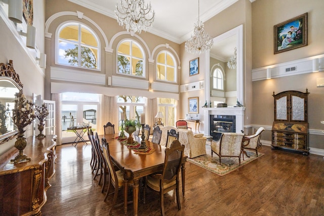 dining area featuring a tile fireplace, wood finished floors, crown molding, and an inviting chandelier