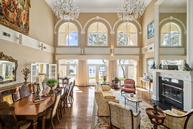 interior space featuring visible vents, ornamental molding, wood finished floors, an inviting chandelier, and a fireplace