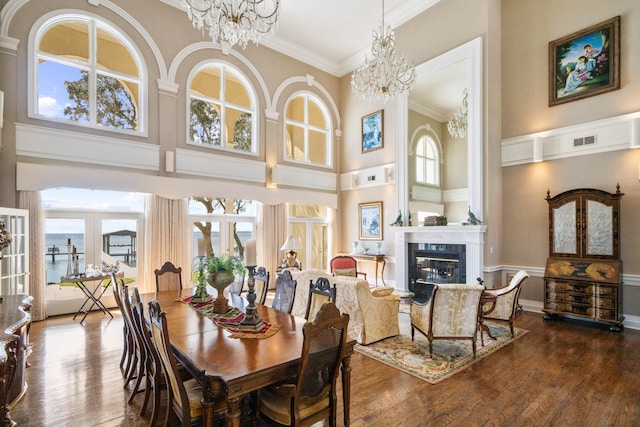 dining room featuring visible vents, a premium fireplace, ornamental molding, wood finished floors, and a chandelier