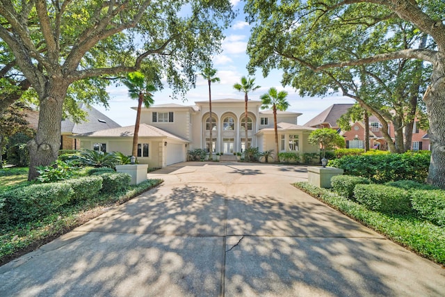 mediterranean / spanish-style home featuring a garage, concrete driveway, and stucco siding