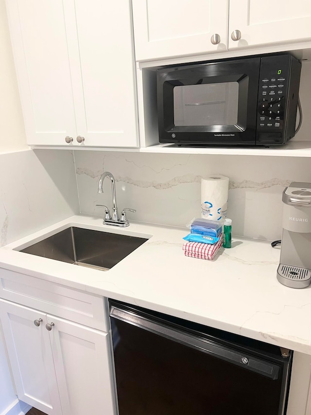 kitchen with light stone counters, sink, white cabinetry, and black appliances