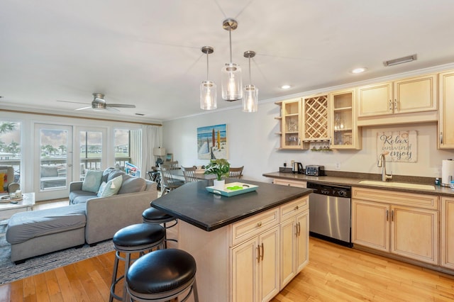 kitchen featuring a kitchen bar, light wood-type flooring, dishwasher, decorative light fixtures, and sink