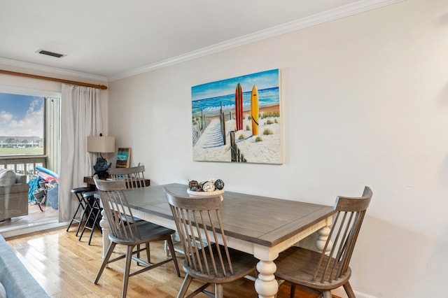 dining space with crown molding and light hardwood / wood-style flooring