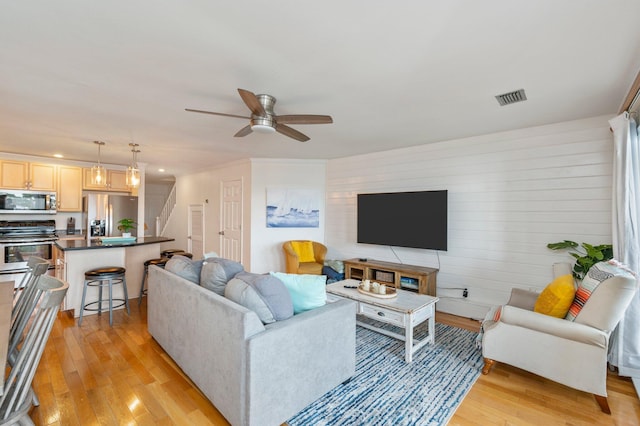 living room featuring light hardwood / wood-style flooring and ceiling fan