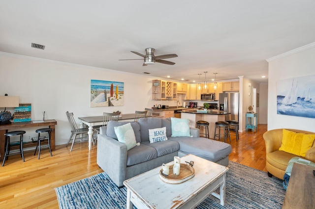 living room featuring ornamental molding, light wood-type flooring, and ceiling fan