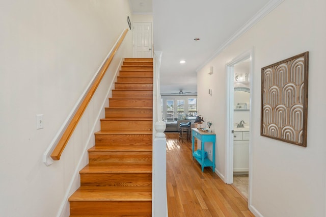 staircase with ornamental molding, sink, wood-type flooring, and ceiling fan