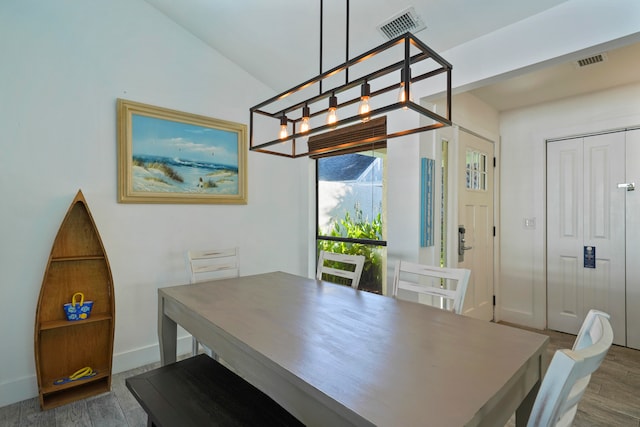 dining space featuring a notable chandelier, lofted ceiling, and dark hardwood / wood-style floors