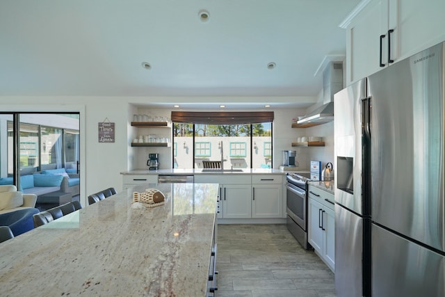 kitchen featuring a healthy amount of sunlight, light stone countertops, stainless steel appliances, and white cabinets