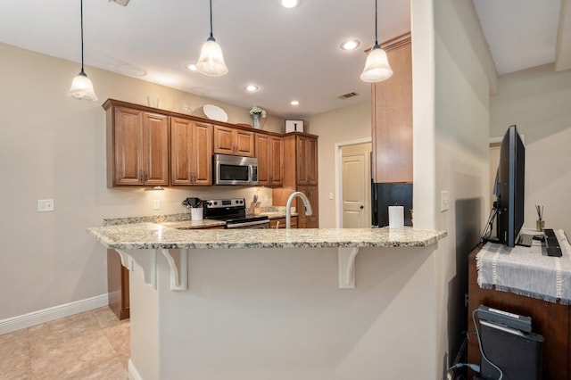 kitchen with appliances with stainless steel finishes, hanging light fixtures, kitchen peninsula, and a breakfast bar