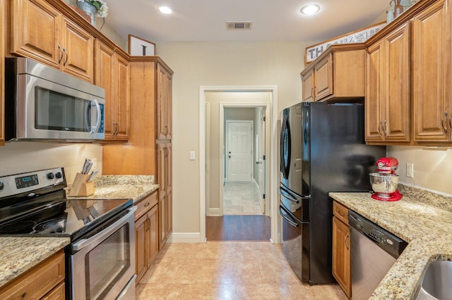 kitchen featuring light stone countertops, appliances with stainless steel finishes, and light tile patterned floors