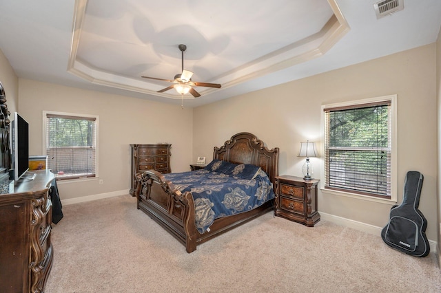 carpeted bedroom featuring ceiling fan, a raised ceiling, and multiple windows