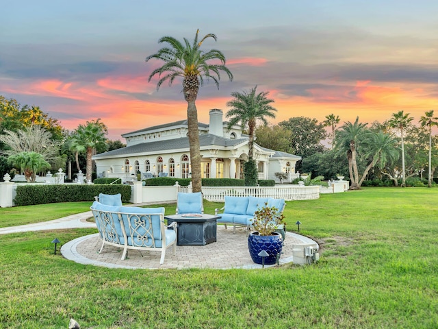 back house at dusk with a patio area, a yard, and an outdoor living space with a fire pit