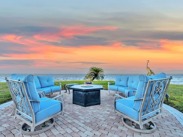 patio terrace at dusk featuring a water view and an outdoor living space with a fire pit