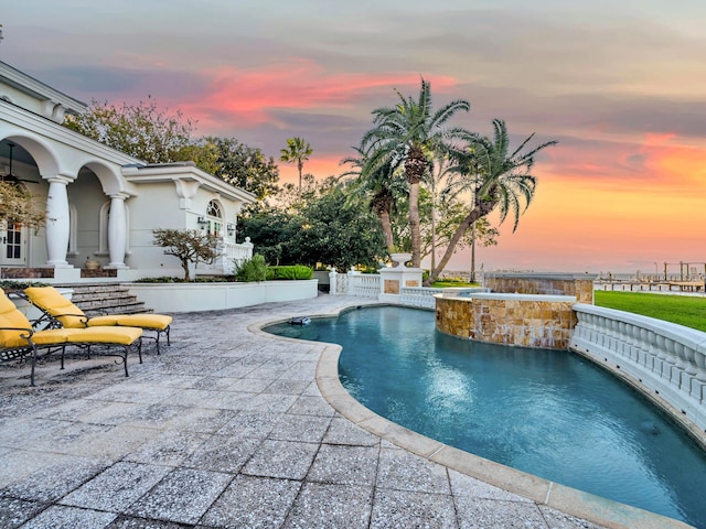 pool at dusk featuring an in ground hot tub and a patio area